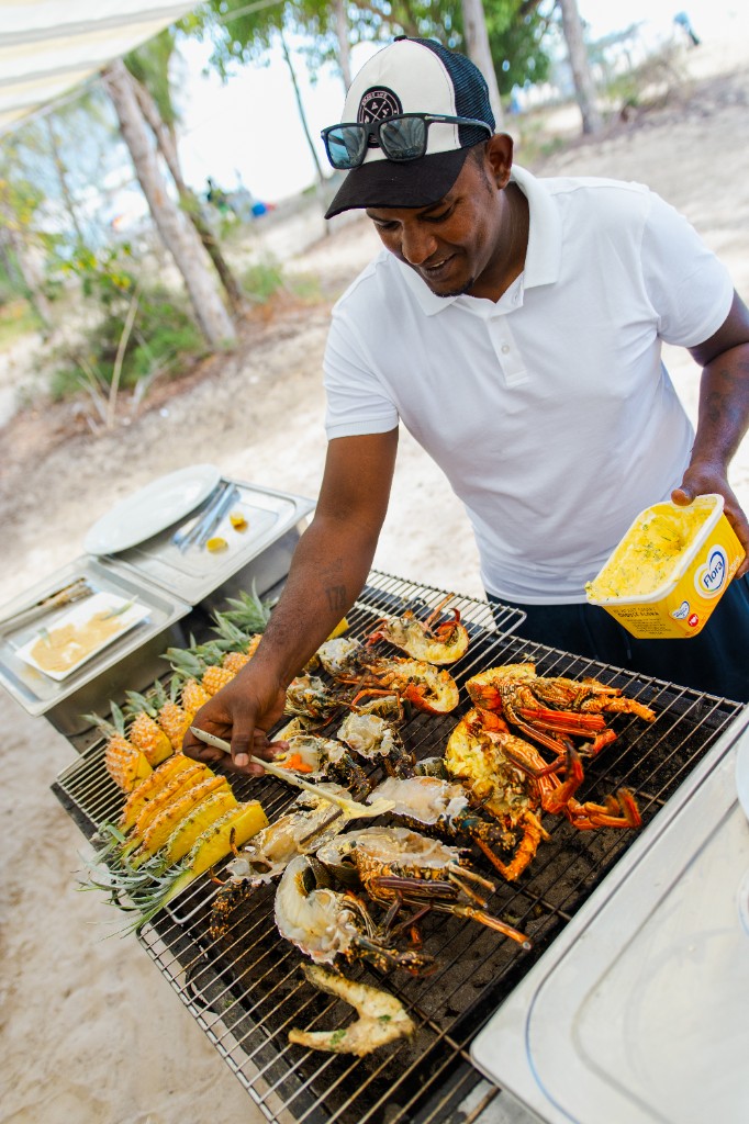 Chef grilling fresh lobster, fish and pineapple on the island BBQ